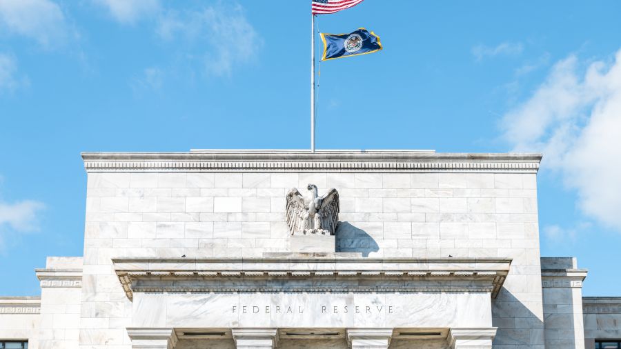 Closeup of Federal Reserve bank facade entrance, architecture building, eagle statue American flags, blue sky at sunny day